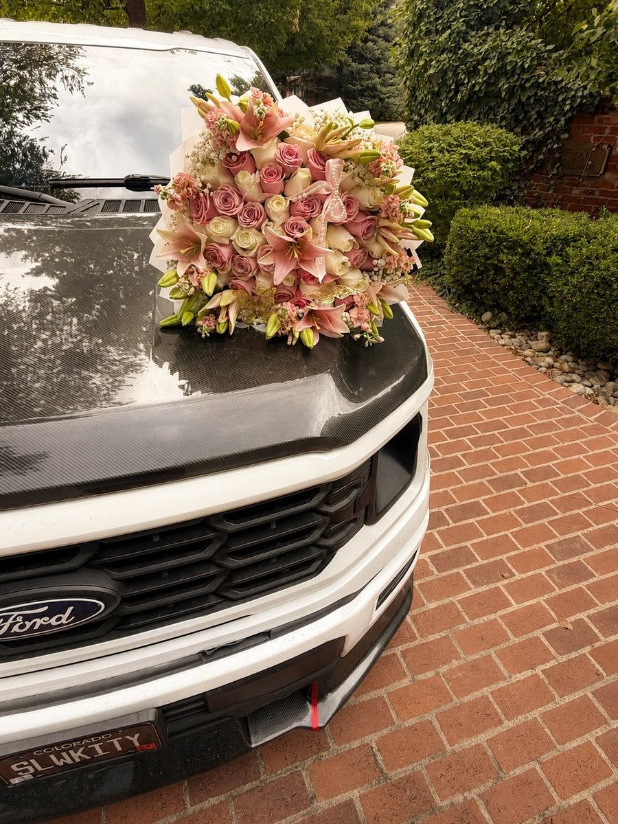 Ale's pink lily bouquet delivered onto the hood of a white truck